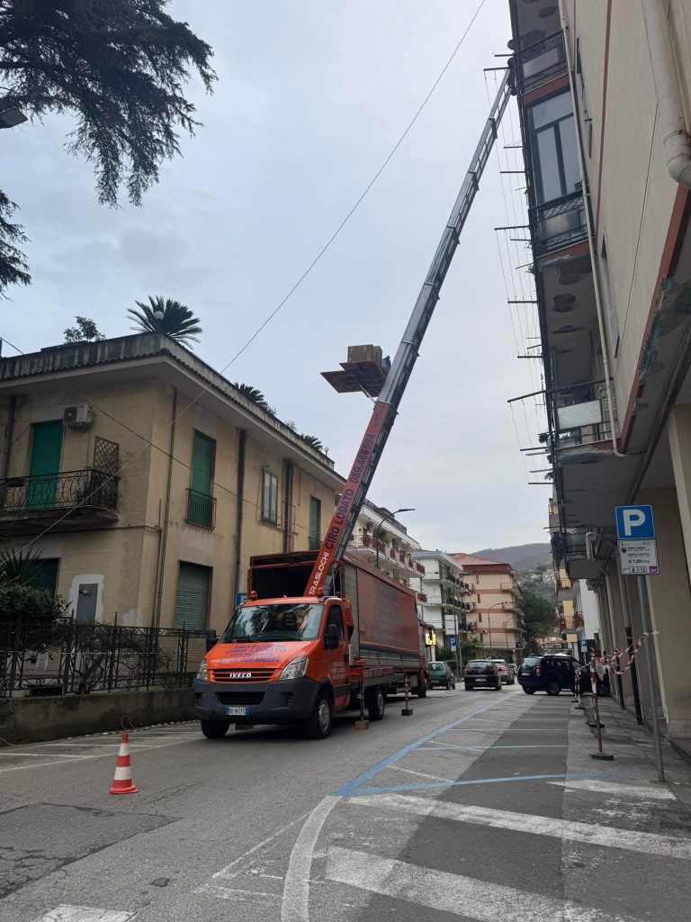 Camion Ciro Lodato Traslochi con autoscala alzata in una via cittadina, area delimitata da coni